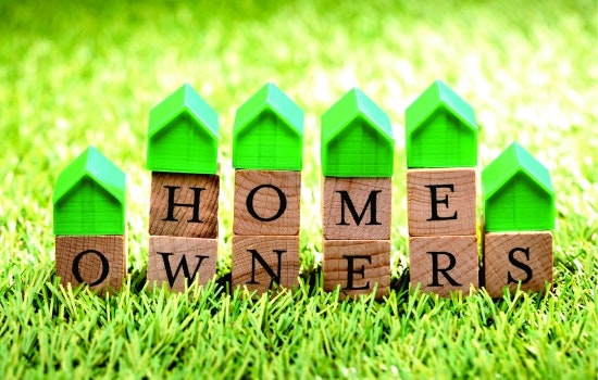 The image features wooden blocks spelling "HOME OWNERS" with small green house figures on top, set against a grassy background.