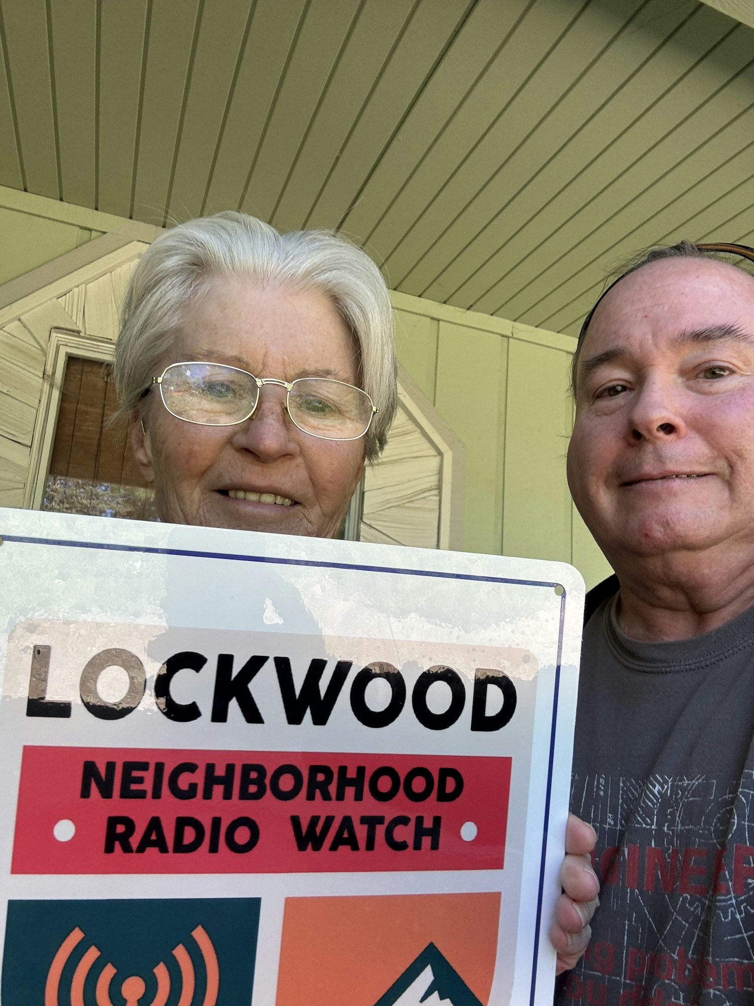 Two people holding a "Lockwood Neighborhood Watch Radio" sign.