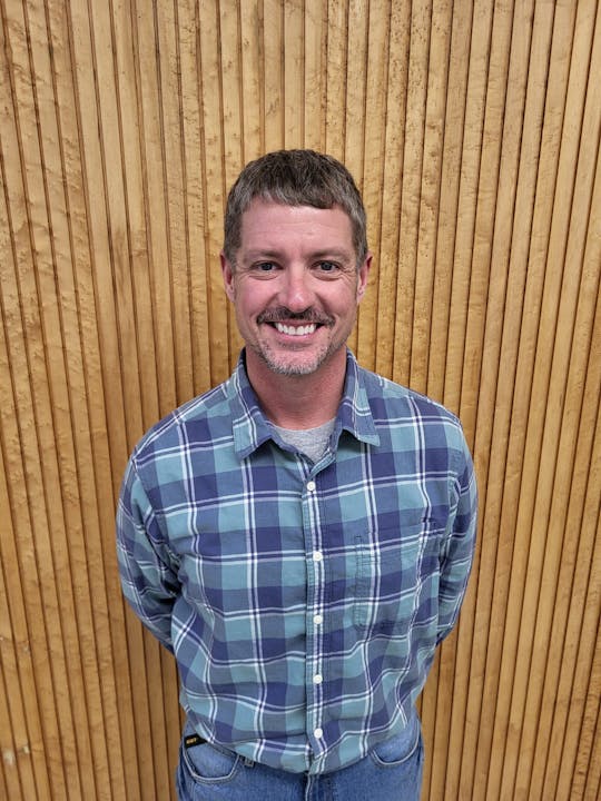 May contain: face, head, person, photography, portrait, indoors, interior design, clothing, shirt, wood, adult, male, man, jeans, pants, happy, and smile