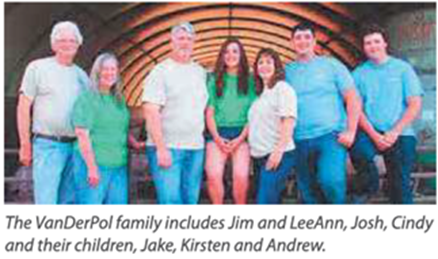 A group of seven people standing together under an archway, smiling at the camera.