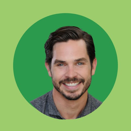 A smiling man with dark hair in a circular green frame.