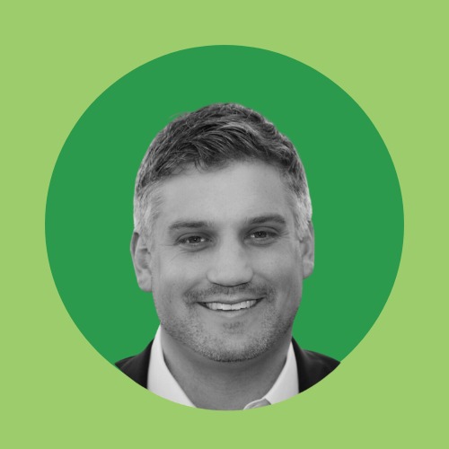 A greyscale photo of a smiling man with a green circular background.