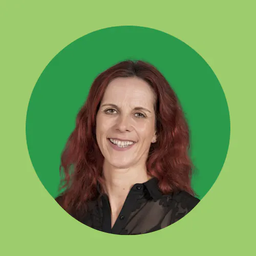 A person with reddish-brown hair smiling, set against a green circular background.