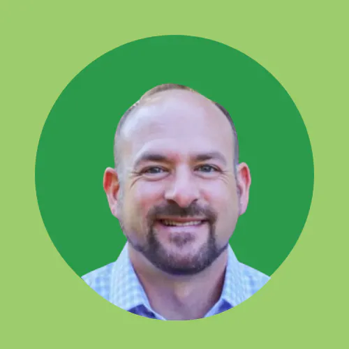 A man smiling, wearing a checkered shirt, on a green circular background.
