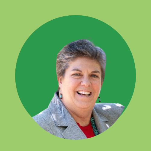 A smiling person with short hair, wearing a jacket and red shirt, in front of a green circular background.