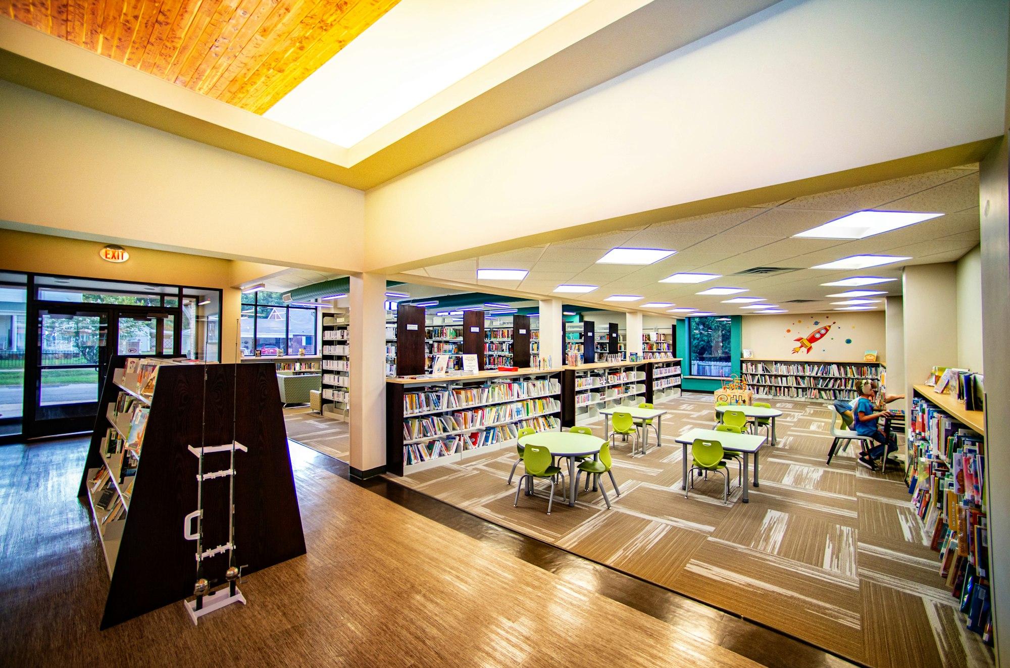 Bright library interior with bookshelves, chairs, and wood ceiling.