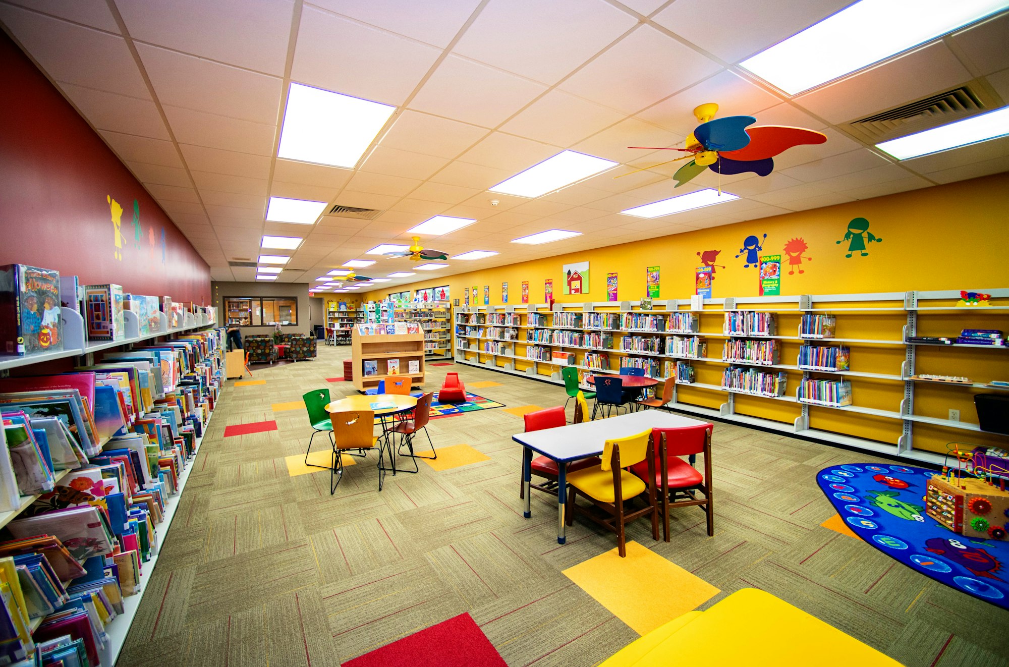 Colorful children's library with books, tables, chairs, and playful decor.