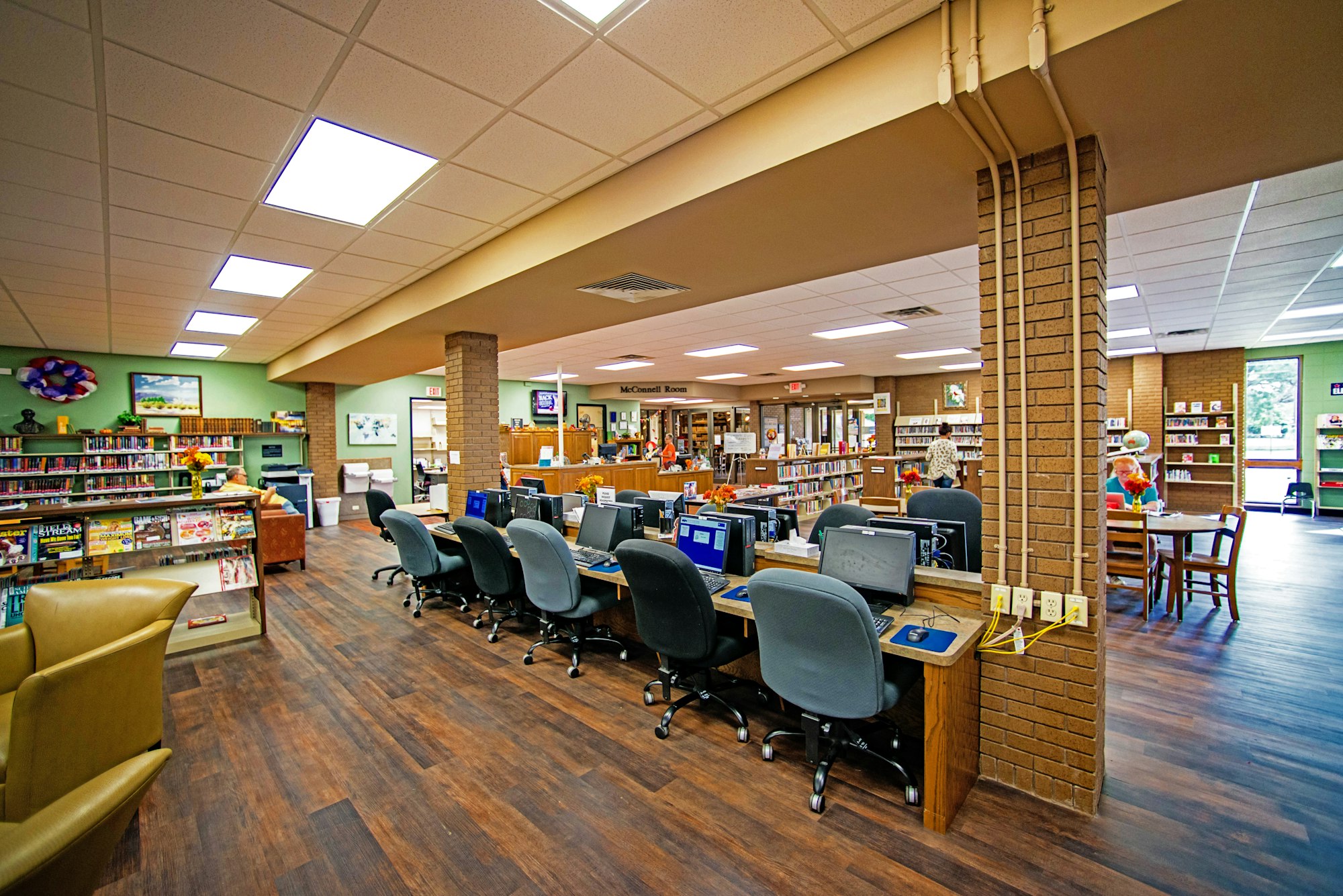 A library interior with computers, bookshelves, and patrons.