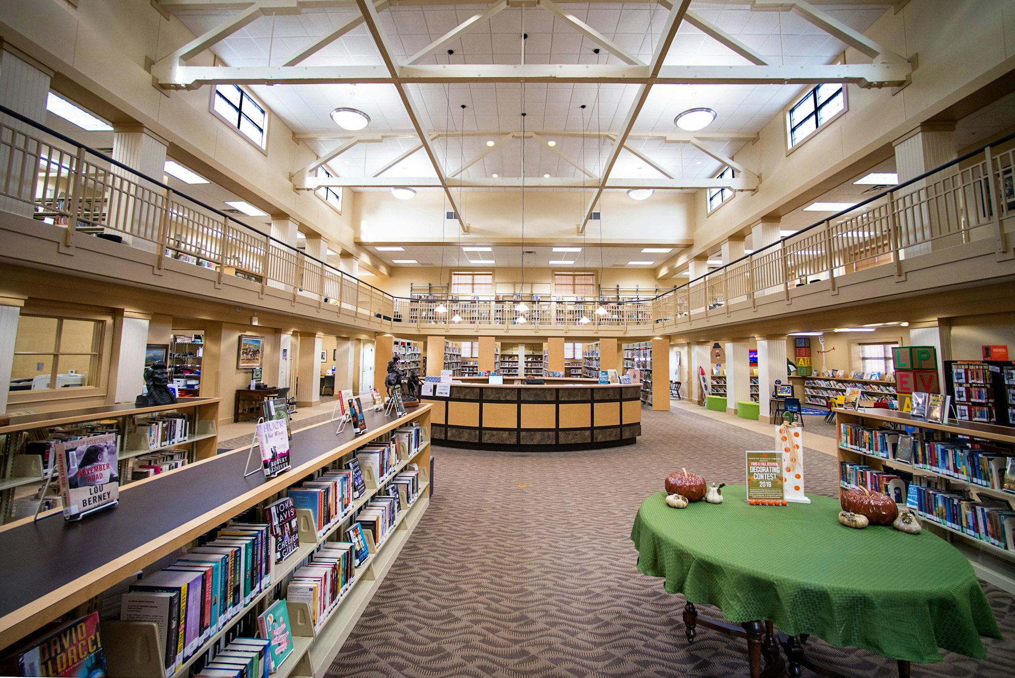 A spacious library interior with bookshelves, reading areas, and a second-floor gallery.