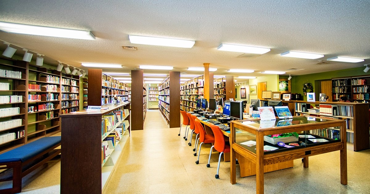 Bookshelves, computers on desks, and chairs in a library setting.