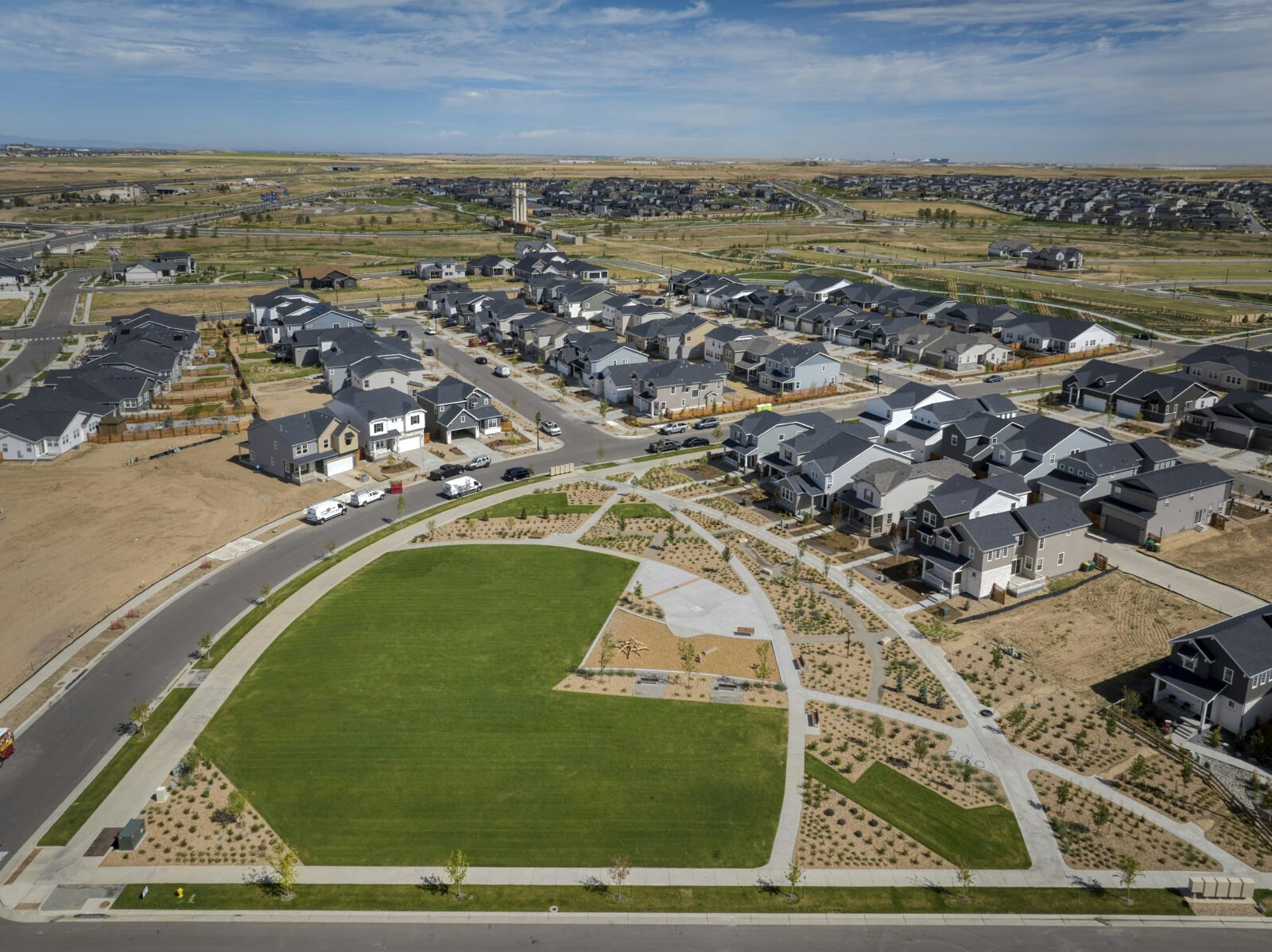 Aerial view of a suburban neighborhood with neatly arranged houses, roads, and a central green park area.