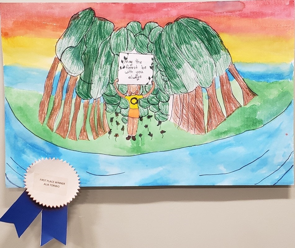 A child's drawing of a forest with a figure holding a sign, a rainbow, and a "First Place Winner" ribbon.