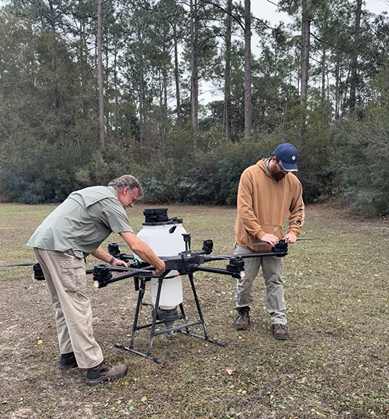 Drone operators preparing the drone for surveillance of large, wooded area.