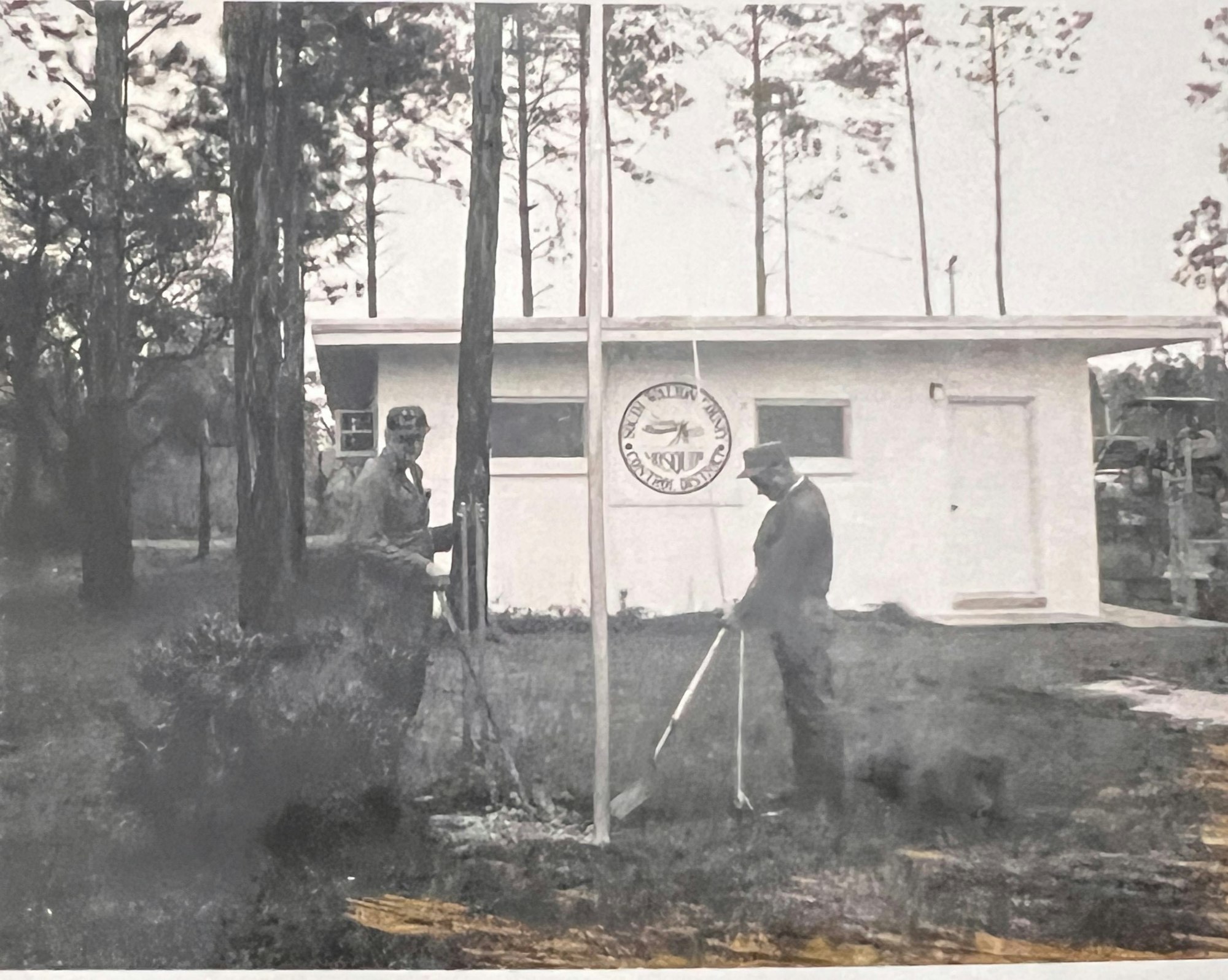 Historical photo of two men setting up flag pole in front of SWCMCD Business office