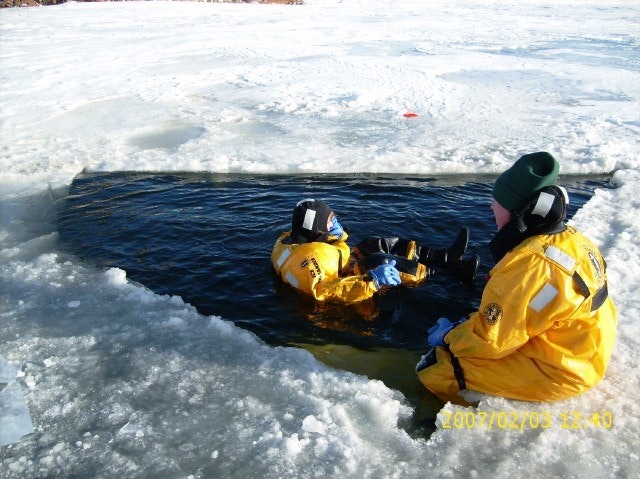 May contain: clothing, lifejacket, vest, coat, person, helmet, transportation, vehicle, watercraft, hat, and ice
