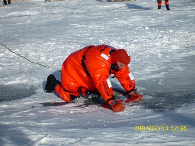 May contain: clothing, lifejacket, vest, person, footwear, shoe, glove, coat, jacket, ice, outdoors, nature, and helmet