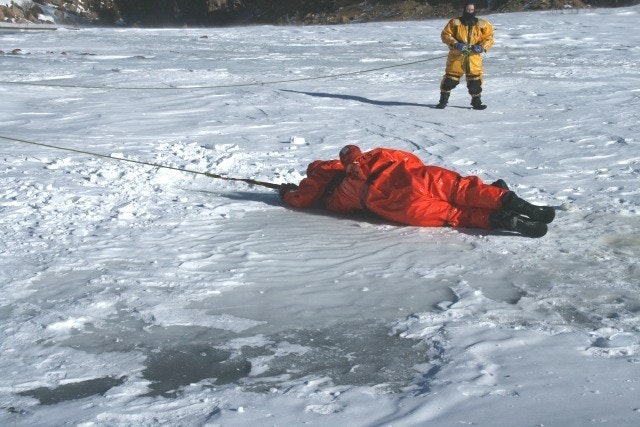 May contain: person, clothing, glove, footwear, shoe, coat, lifejacket, vest, ice, and helmet