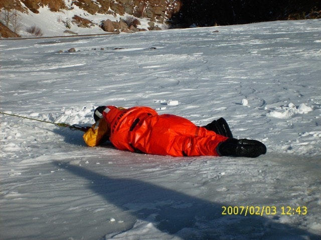 May contain: clothing, coat, lifejacket, vest, jacket, glove, person, outdoors, ice, accessories, bag, and handbag