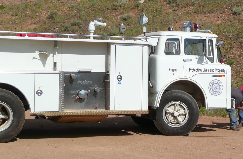 A vintage white fire truck labeled "Engine 2" with "Protecting Lives and Property" on the side.