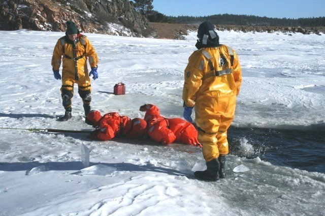 May contain: clothing, glove, person, coat, hat, rescue, lifejacket, vest, footwear, and shoe