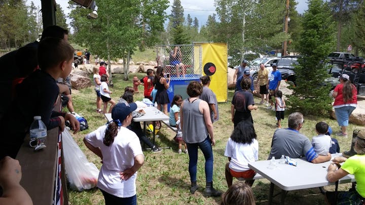 May contain: grove, land, nature, outdoors, plant, tree, vegetation, woodland, grass, park, person, architecture, building, shelter, accessories, bag, handbag, clothing, hat, footwear, shoe, people, camping, desk, furniture, table, and glove