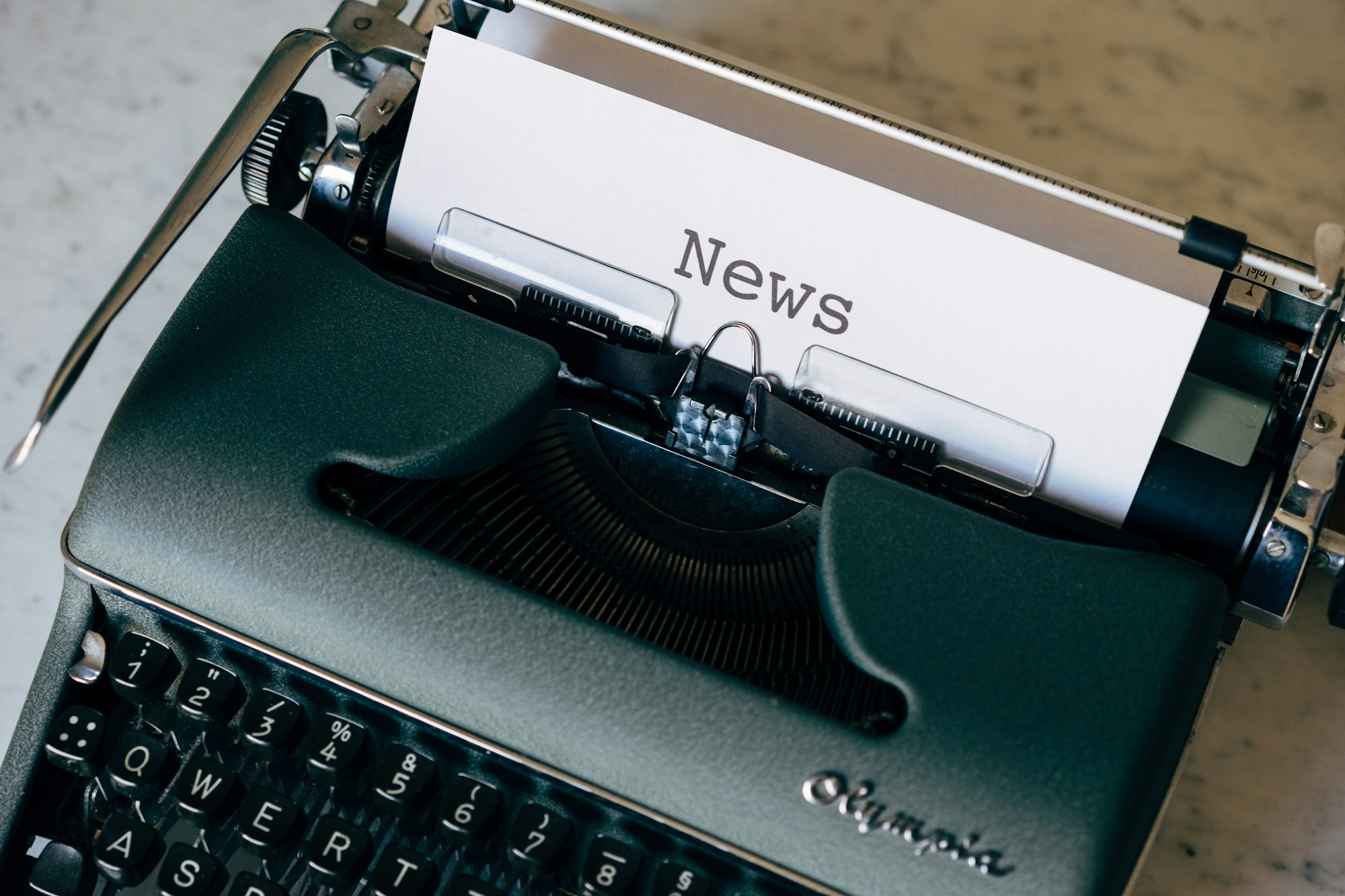 Old typewriter with a piece of paper in it on which is typed "News."
