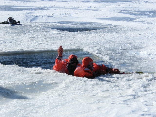 May contain: clothing, vest, lifejacket, glove, person, ice, hat, transportation, vehicle, watercraft, and water