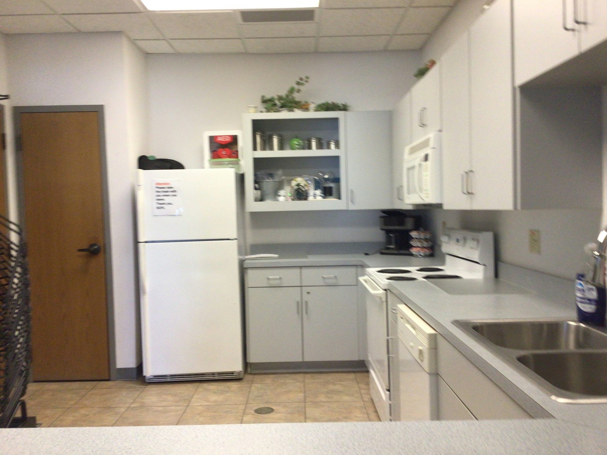 A modern kitchen with, stove, fridge, sink, microwave, dishwasher and coffee maker