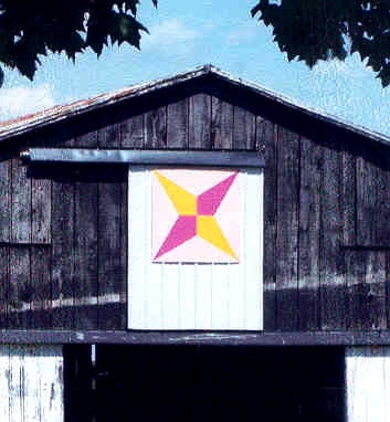 A barn with a quilt pattern featuring a colorful star design.