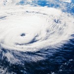 Aerial view of a hurricane with a distinct eye, swirling clouds over the ocean.