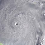 An aerial view of a hurricane with a well-defined eye, swirling clouds, and intense weather systems.