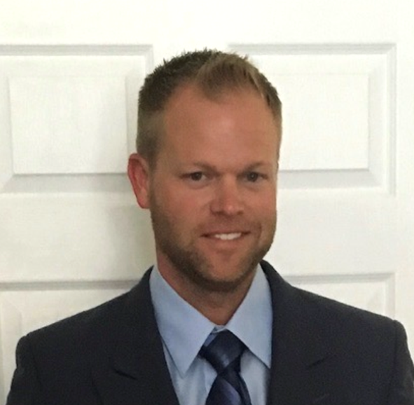 A person in a suit and tie standing in front of a white door.