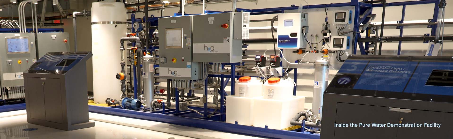 Industrial water purification system with control panels, pipes, and processing equipment in a demonstration facility.