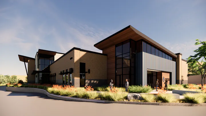 A modern building with large windows, wooden accents, and landscaped greenery, likely an office or community space.