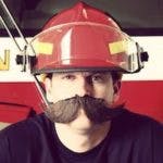 A person with a firefighter helmet and a large mustache.