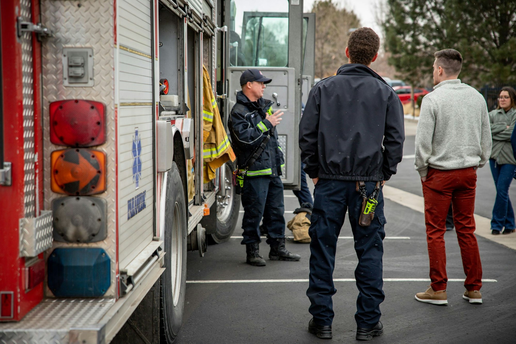 Firefighters and civilians stand near a fire truck, possibly in discussion.