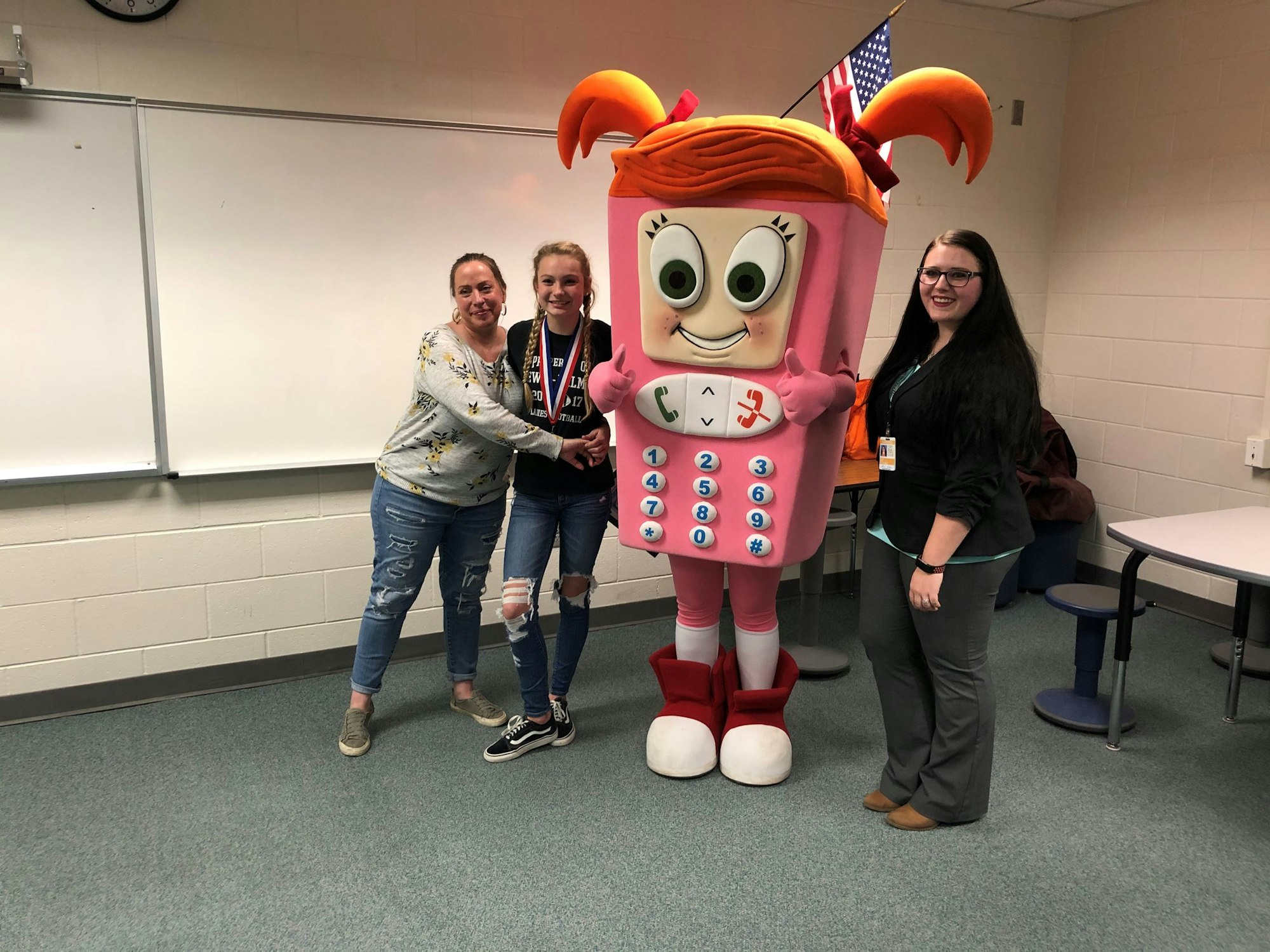 Three people posing with a person in a pink cartoon phone costume.
