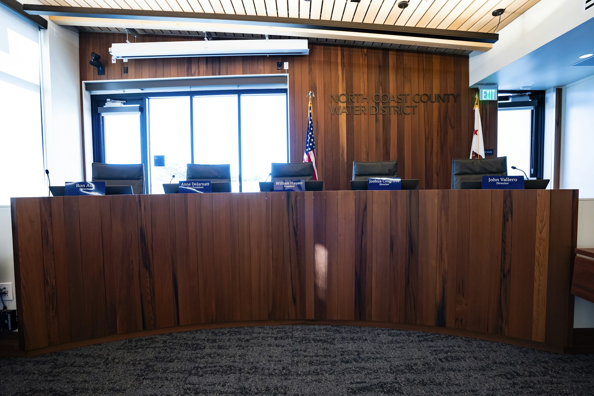 A meeting room for the North Coast County Water District, featuring a wooden panel and several empty seats for directors.