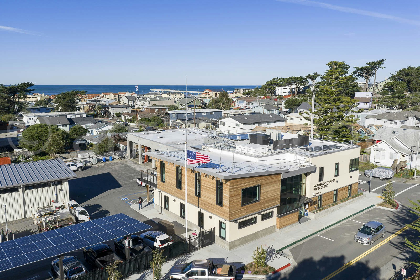 A modern building housing the North Coast County Water District, surrounded by residential areas and near the ocean.