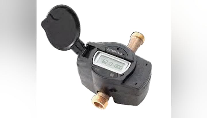 A digital water meter with a display and open cover, connected to brass fittings.