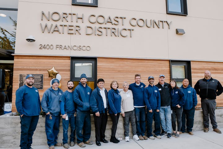 A group of employees stands outside the North Coast County Water District building, showcasing teamwork and community.