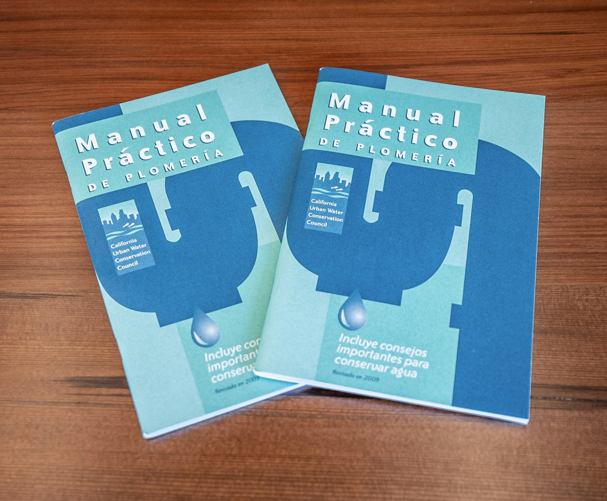 Two copies of a blue manual titled "Manual Práctico de Plomería," focused on plumbing and water conservation tips.