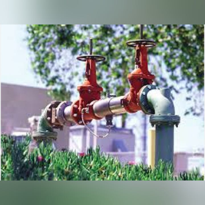 The image shows a machinery setup featuring orange valves and pipes, surrounded by greenery, likely related to water management or irrigation.
