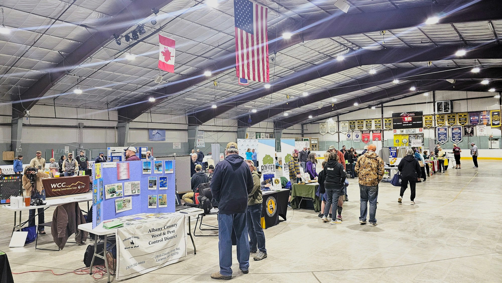 An indoor event with booths, people, and flags of the USA and Canada.
