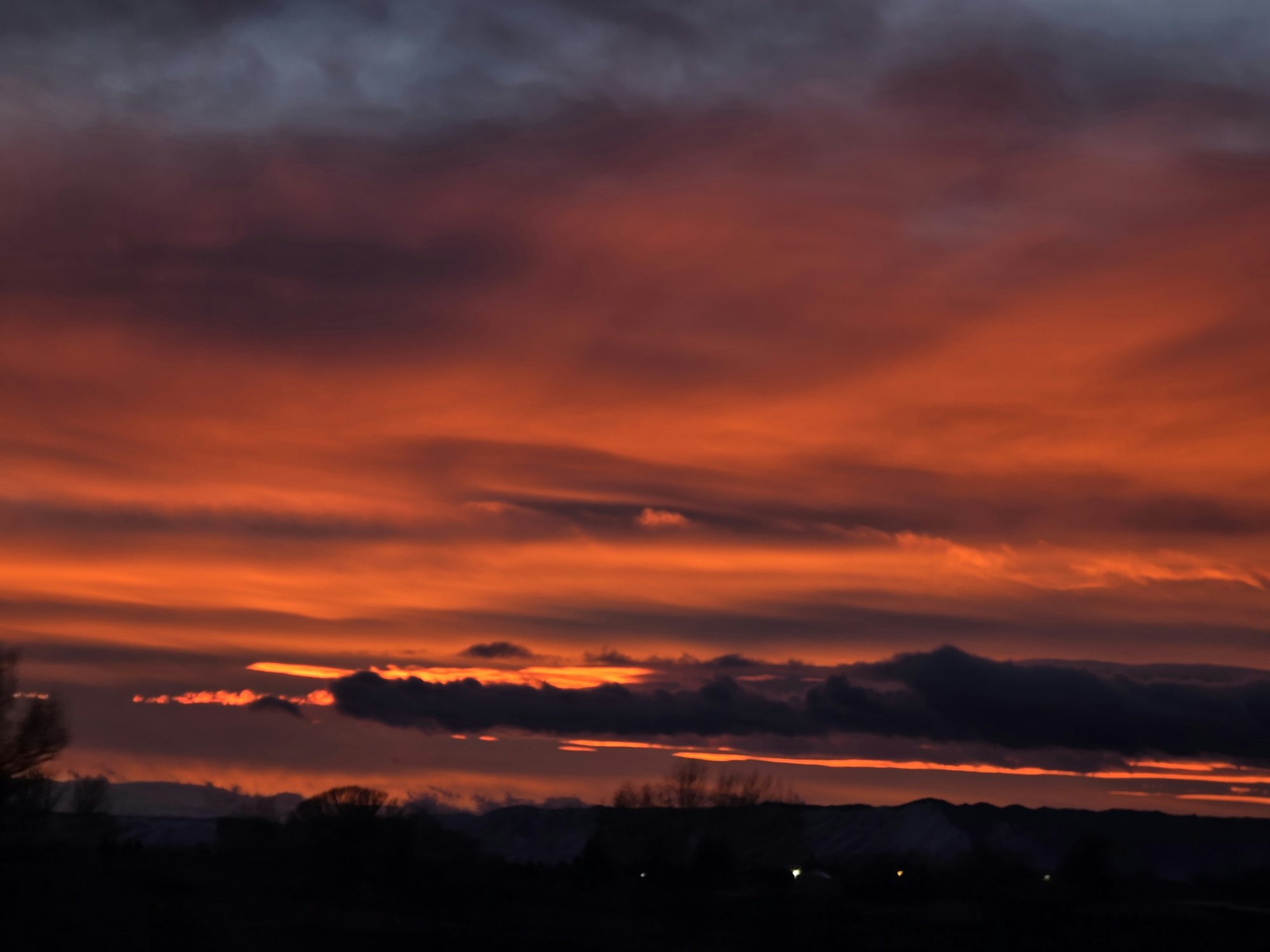 A vibrant sunset with striking orange and purple hues blending across the sky, suggesting a serene evening atmosphere.