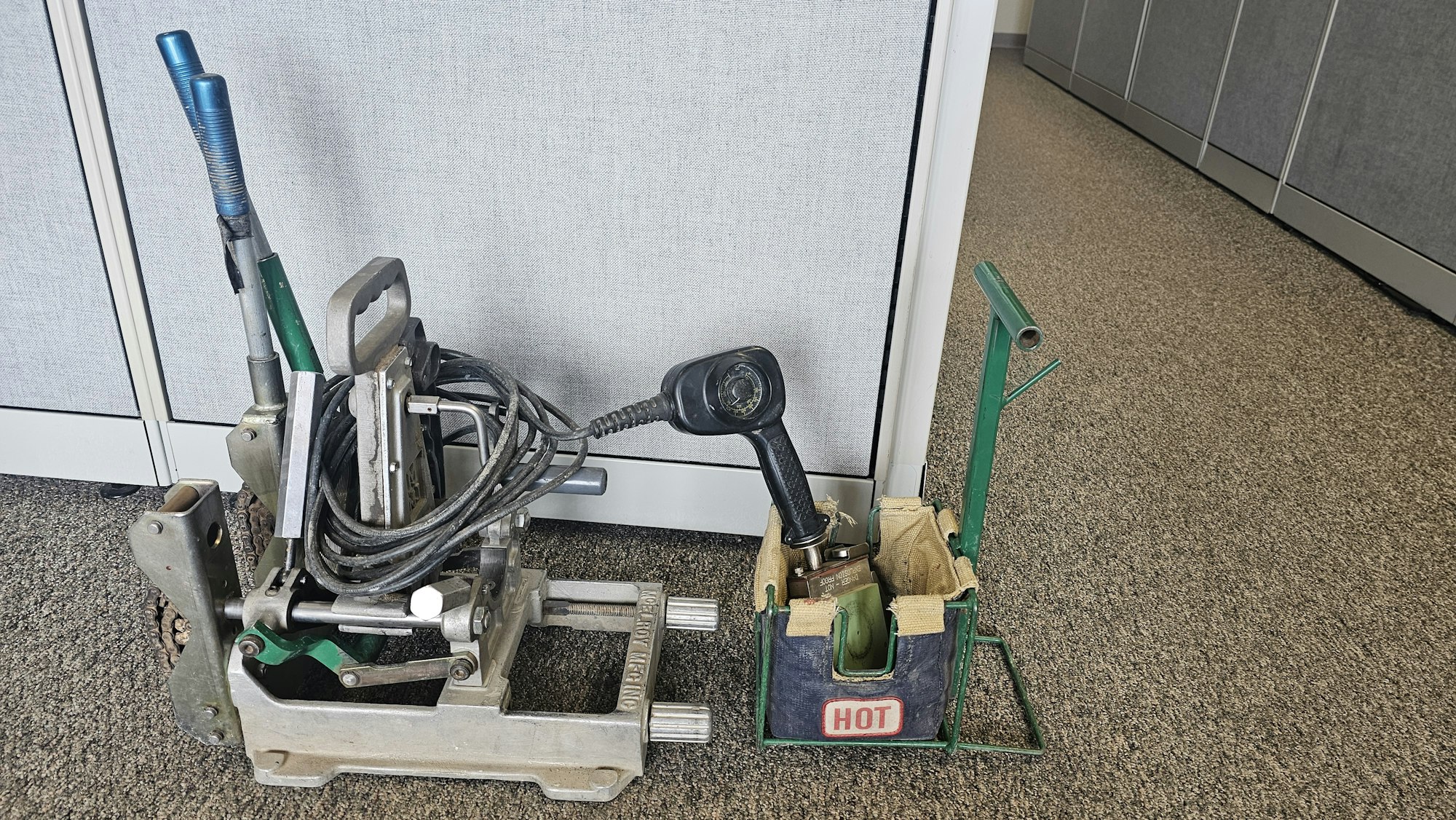 Old carpet installation tools against a cubicle wall.