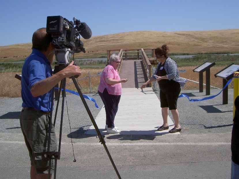Dorothy Sakasaki cutting ribbon at McNabney marsh platform, camera man with camera