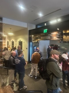 People standing in line inside a building, possibly waiting for service or food.