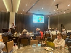 A presenter and audience in a conference room with a projected presentation.