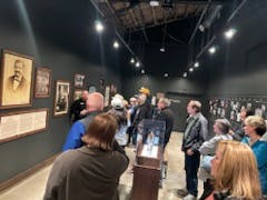 A group of people observing artwork in a gallery exhibition.